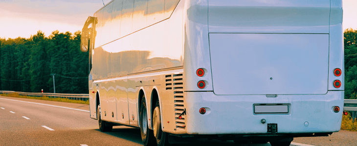 a white charter bus drives on the highway