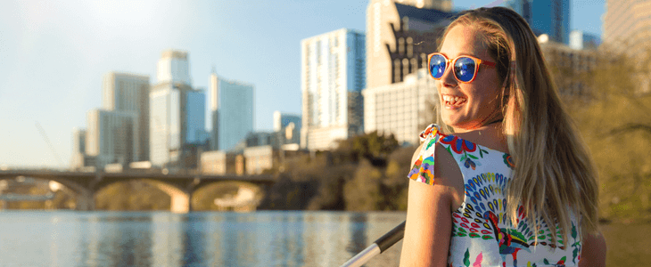 a young woman with sunglasses smiles at the camera