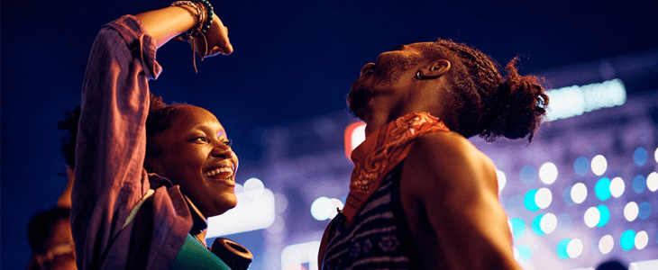 a young african american couple smiles and dances at a concert