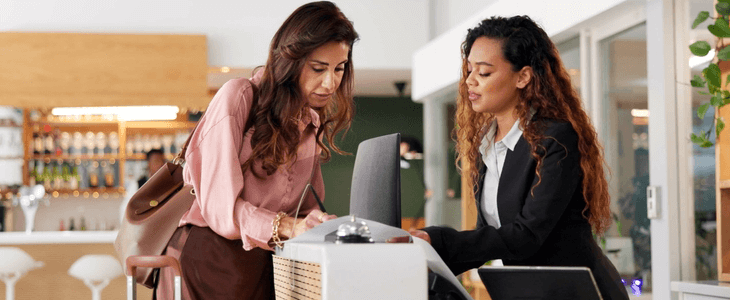 a hotel staff members assists a guest at the desk