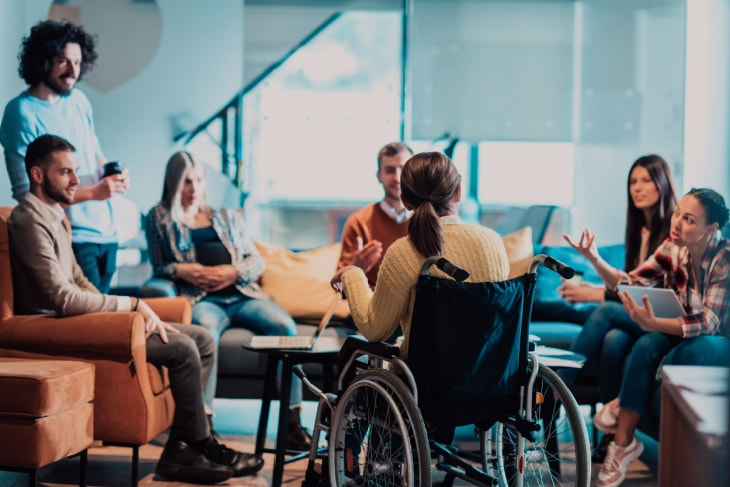 A woman in a wheelchair meets with her colleagues 