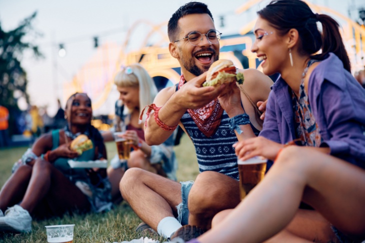 Young couple shares a burger at a food festival